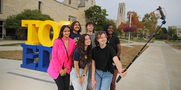 UToledo students posing in front of TOL-EDO statue with a selfie stick